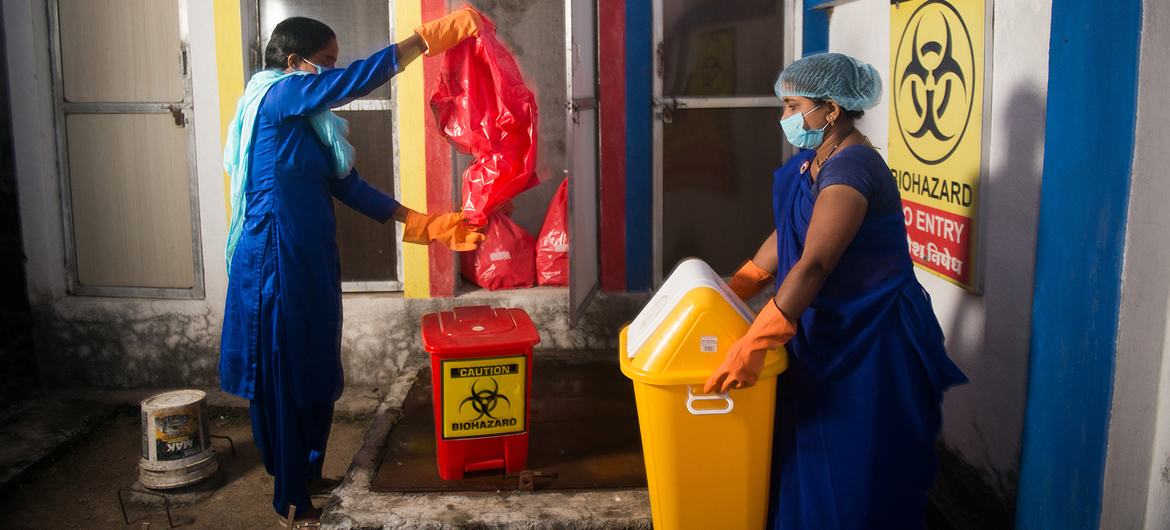 Уборщицы выбрасывают мусор во временное хранилище биомедицинских отходов в медицинском центре в Индии.