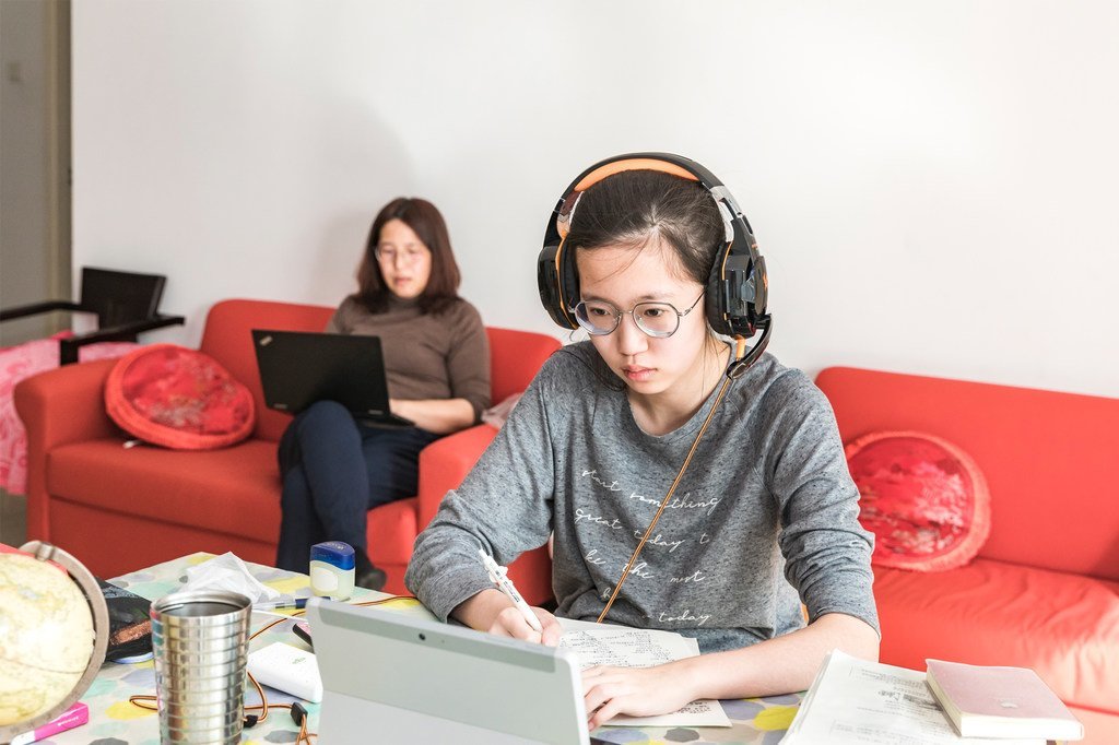 今年2月的北京，小雨（音）正在上网课，母亲坐在沙发上远程工作。