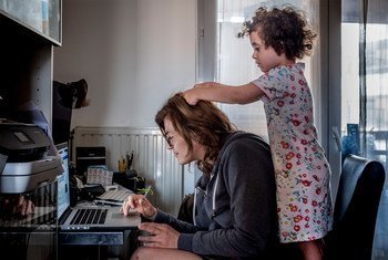 फ़्रांस के लियोन में तालाबन्दी के दौरान एक पत्रकार घर से काम कर रही हैं और उनकी बेटी उनके साथ खेल रही है. 