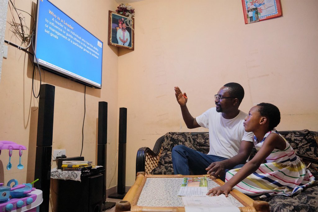 10岁的加纳女孩德波拉正在通过电视上网课，父亲富兰克林在一旁辅导。