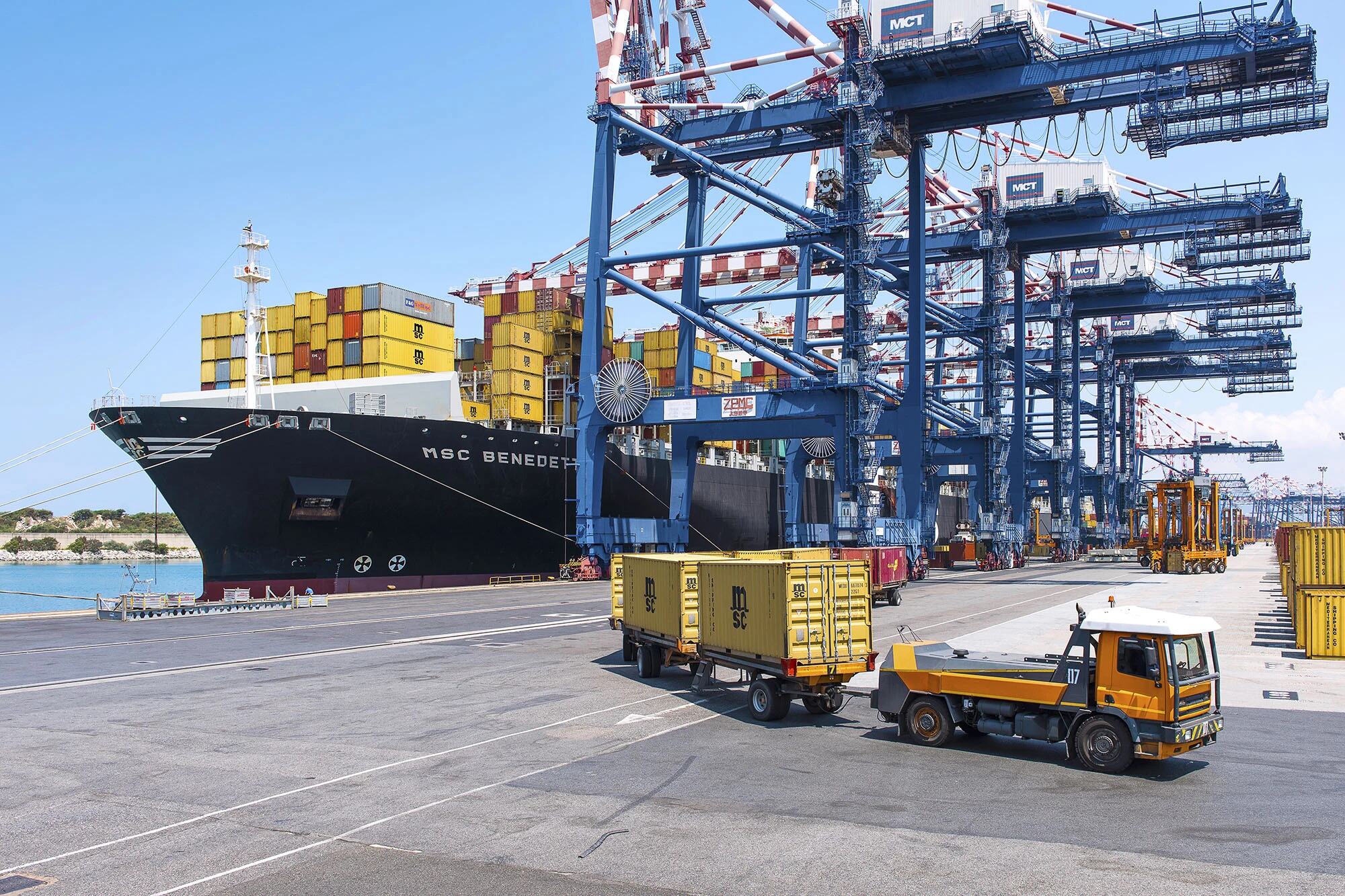 MSC Benedetta container ship docked at the port of Gioia Tauro, Italy, with cranes and port vehicles in the foreground.