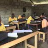 Wanafunzi waliovaa sare za njano na chungwa wamekaa kwenye madawati darasani katika Chuo cha Exodus huko Juba, Sudan Kusini.