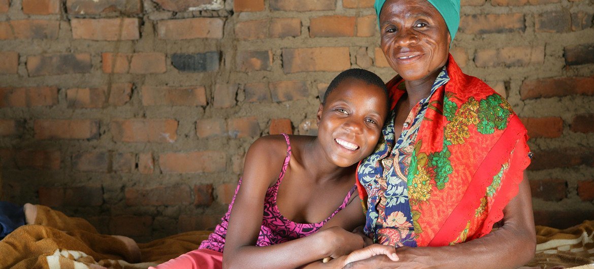 Une femme séropositive est assise chez elle avec sa petite-fille à Mangwe, au Zimbabwe.