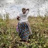 Une agricultrice au milieu d'un essaim de criquets pèlerins se nourrissant de cultures dans le comté de Kitui, au Kenya.