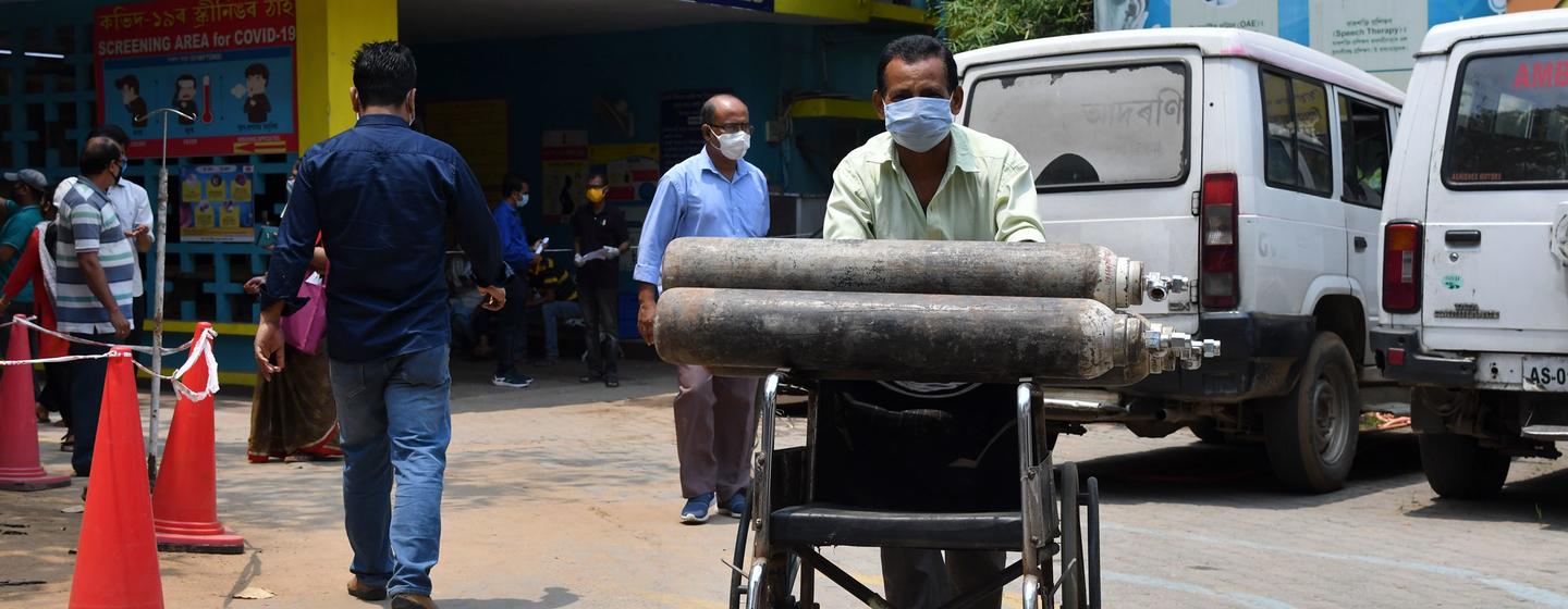 Un trabajador sanitario traslada bombas de oxígeno  en un carrito, en Guwahati, (India).