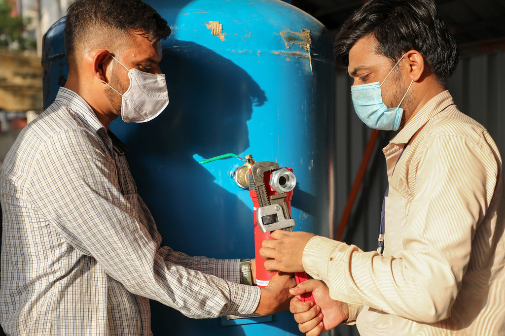 Dos trabajadores instalaron bombas de oxígeno para el tratamiento de pacientes con enfermedades respiratorias, en la India.