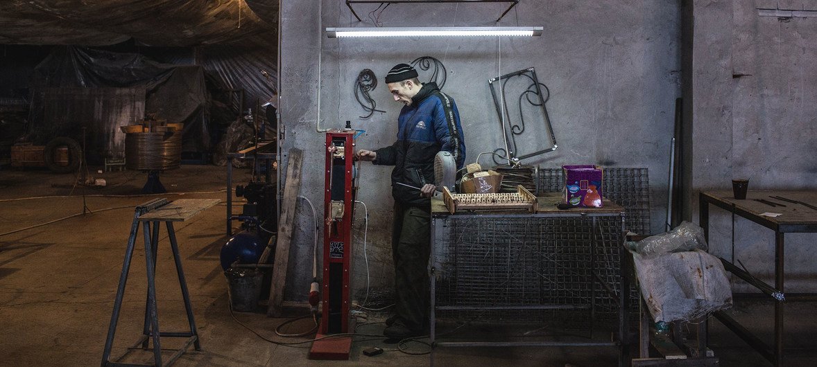 乌克兰东部因冲突而流离失所的一名工人正在金属加工厂修理机器。