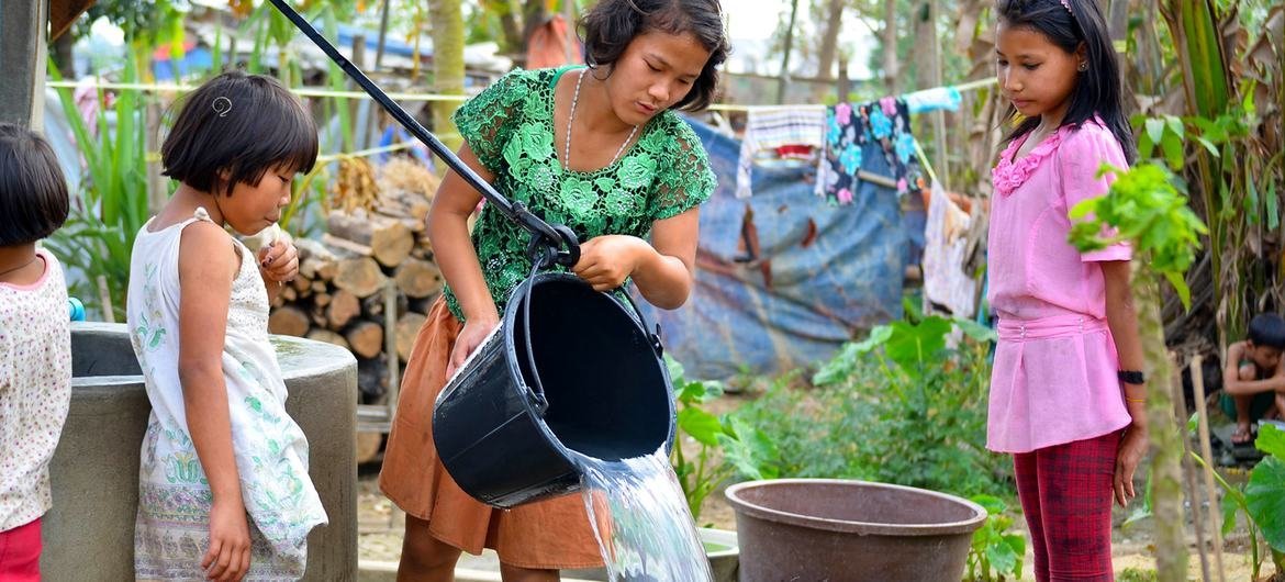 Unas niñas desplazadas en un campo de Myanmar recogen agua de un pozo