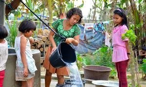 缅甸一个流离失所者营地里的年轻女孩在从水井里取水。 