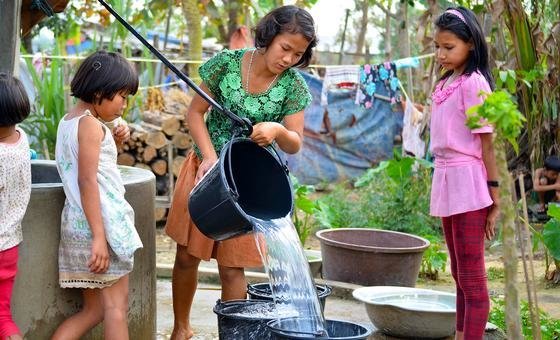 Young girls in a displaced persons camp in Myanmar collect water from a well.