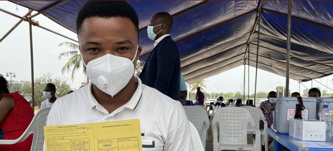 Machad, un trabajador de salud en Benin muestra su tarjeta de vacunación con su primera dosis de AstraZeneca.