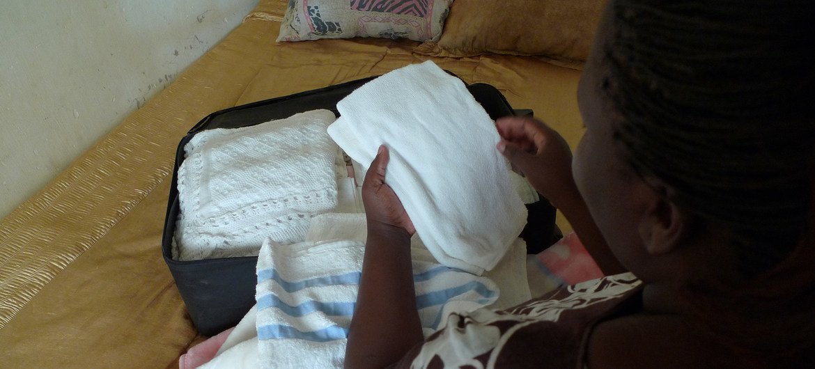 De retour de la naissance de son bébé mort-né, une femme déballe les vêtements et couvertures prévus pour bébé dans sa maison à Lusaka. 