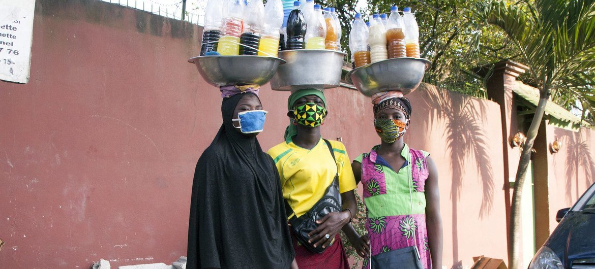 Tres mujeres con mascarilla venden medicinas en las calles de Abidjan durante la pandemia de COVID-19.
