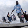Des Haïtiens s'enfuyant avec des marchandises volées dans un bâtiment effondré à Port-au-Prince.