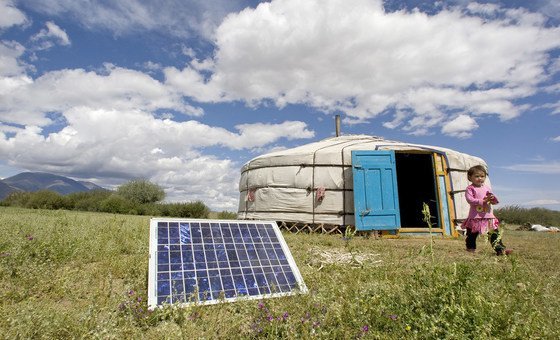 Une famille en Mongolie avec un panneau solaire à côté d'une tente traditionnelle.