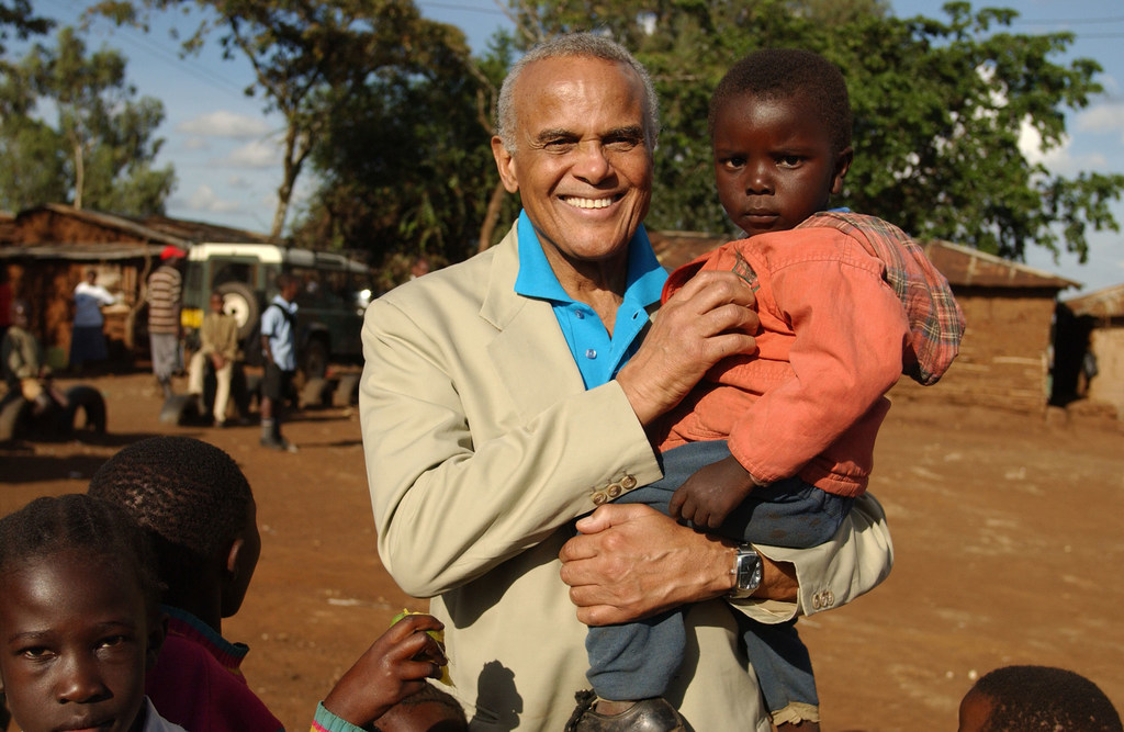 L'Ambassadeur itinérant de l'UNICEF Harry Belafonte tient un tout-petit, debout avec d'autres enfants dans la section Makina du bidonville de Kibera à Nairobi, au Kenya.