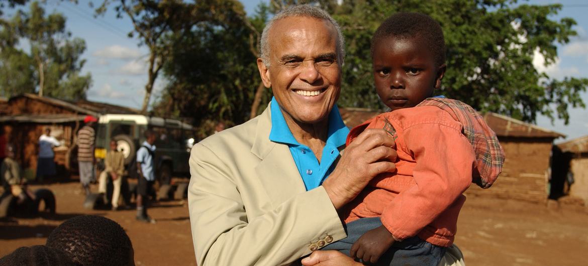 UNICEF Goodwill Ambassador Harry Belafonte holds a toddler while standing with other children in Kibera, Nairobi, Kenya.