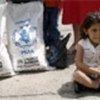 Ecuadorian refugee girl sitting next to food rations