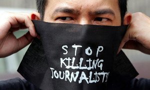 Un homme portant un masque où est inscrit le message : « arrêter de tuer les journalistes ».