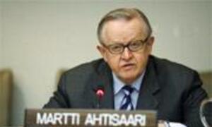 Martti Ahtisaari speaking at a podium with a nameplate during a formal meeting.