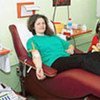 A woman gives blood while her children look on