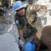 UN peacekeeper holds the hand of a student buried under the rubble