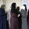 Iraqi women voters stand in line, waiting to enter a polling station