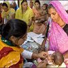 A health worker examines an infant at a busy clinic in South Asia