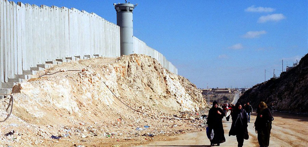 Mujeres palestinas caminando a lo largo del muro de separacón cerca de Ramalá, en Cisjordania.
