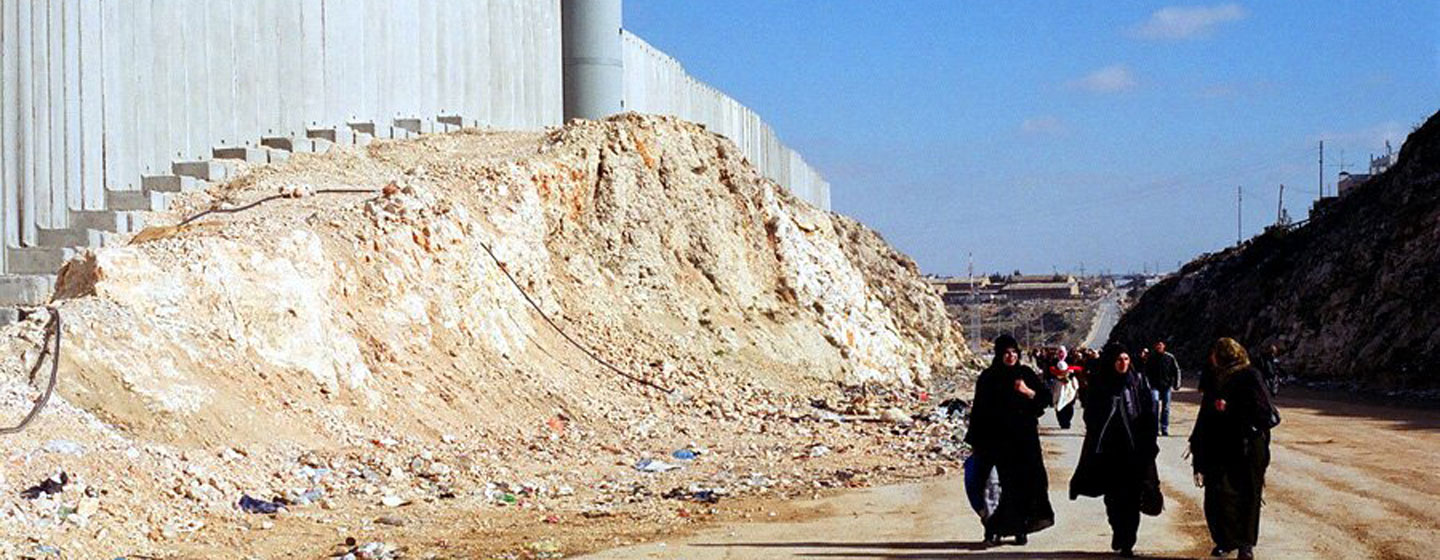 Mulheres palestinas passam pela barreira de Israel perto de Ramallah, na Cisjordânia