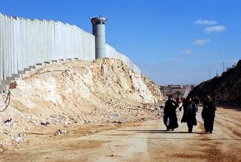 फ़लस्तीनी क्षेत्र - पश्चिमी तट में रामल्लाह के निकट एक इसराइली अवरोधक दीवार के निकट से गुज़रते हुए कुछ महिलाएँ. (फ़ाइल फ़ोटो)