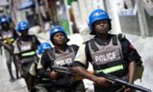 Armed peacekeepers in blue helmets and tactical gear stand in a street.
