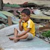 A child sits alone amid the ruins of a collapsed building in Padang, West Sumatra, Indonesia