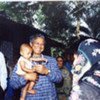 Le Prix Nobel de la paix Muhammad Yunus tenant un enfant alors qu'il rencontre des villageois aidés par sa banque.