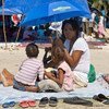 A mother shelters her children from the sun in Cité Soleil, Haiti