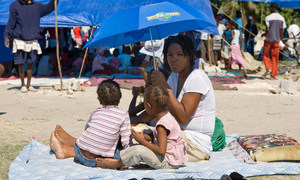 A mother shelters her children from the sun in Cité Soleil, Haiti.