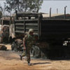 Nigerian soldier runs past a burnt-out truck in Jos