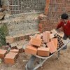 Un enfant transportant des briques dans une brouette.