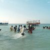 Somalis wade out to smugglers' boats near Bossaso for their voyage crossing