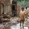 Des Pakistanais marchent dans les rues inondées de la ville de Nowshera.