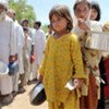 Displaced young girls and men queue up separately for cooked rations in Jalala camp, Pakistan