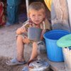 A boy drinks water in the resettlement camp in Khuroson District, Tajikistan