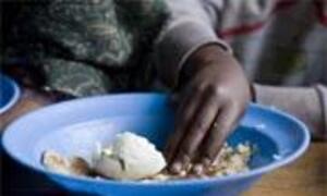 A close-up shows a child's hand reaching into a blue bowl filled with rice and a piece of bread.