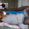 Une femme est allongée à côté de son fils qui reçoit un traitement contre le choléra en Haïti.