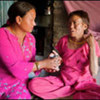 A neighbour provides water for a woman with TB at the Monohara slum in Kathmandu, Nepal