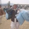 A man displaced by the latest fighting carries aid items distributed by UNHCR