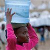 Une jeune fille haïtienne transporte de l'eau à Port-au-Prince.