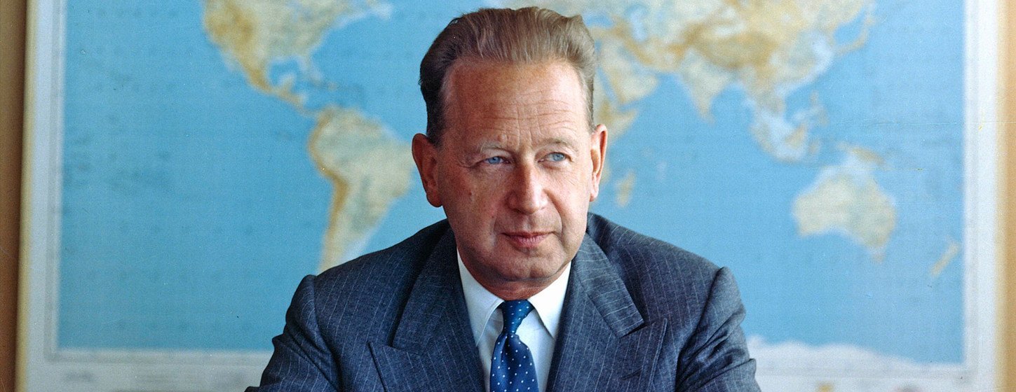 Portrait of Dag Hammarskjöld, Secretary-General of the United Nations, sitting at a desk with a world map in the background.
