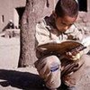 A young boy reading a copy book in Qazin, Iran