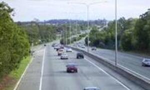 Traffic on a multi-lane highway with cars and a distant overpass.